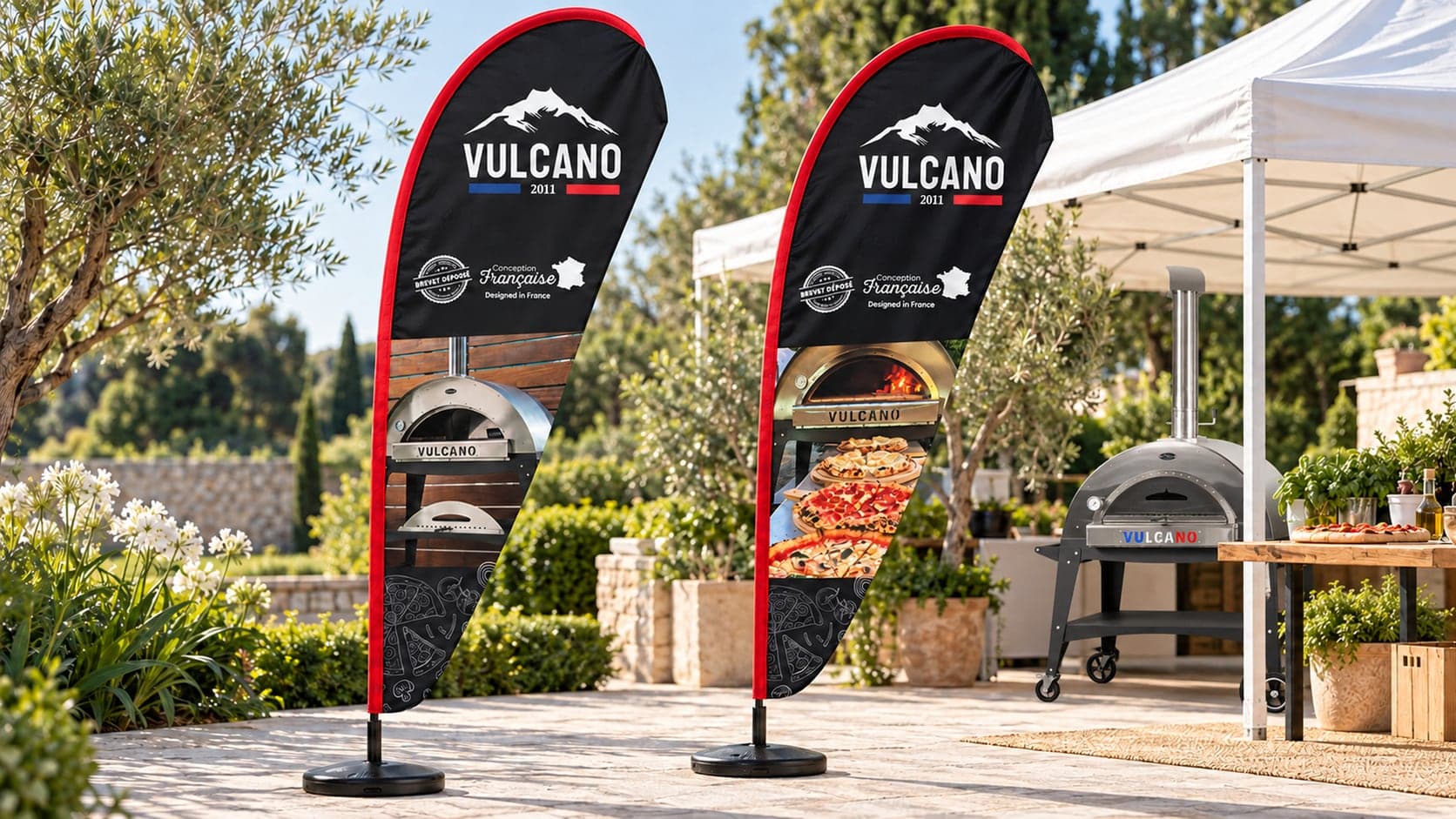 Les deux modèles de drapeaux Vulcano avec bord arrondi rouge dans un décor de foire extérieure